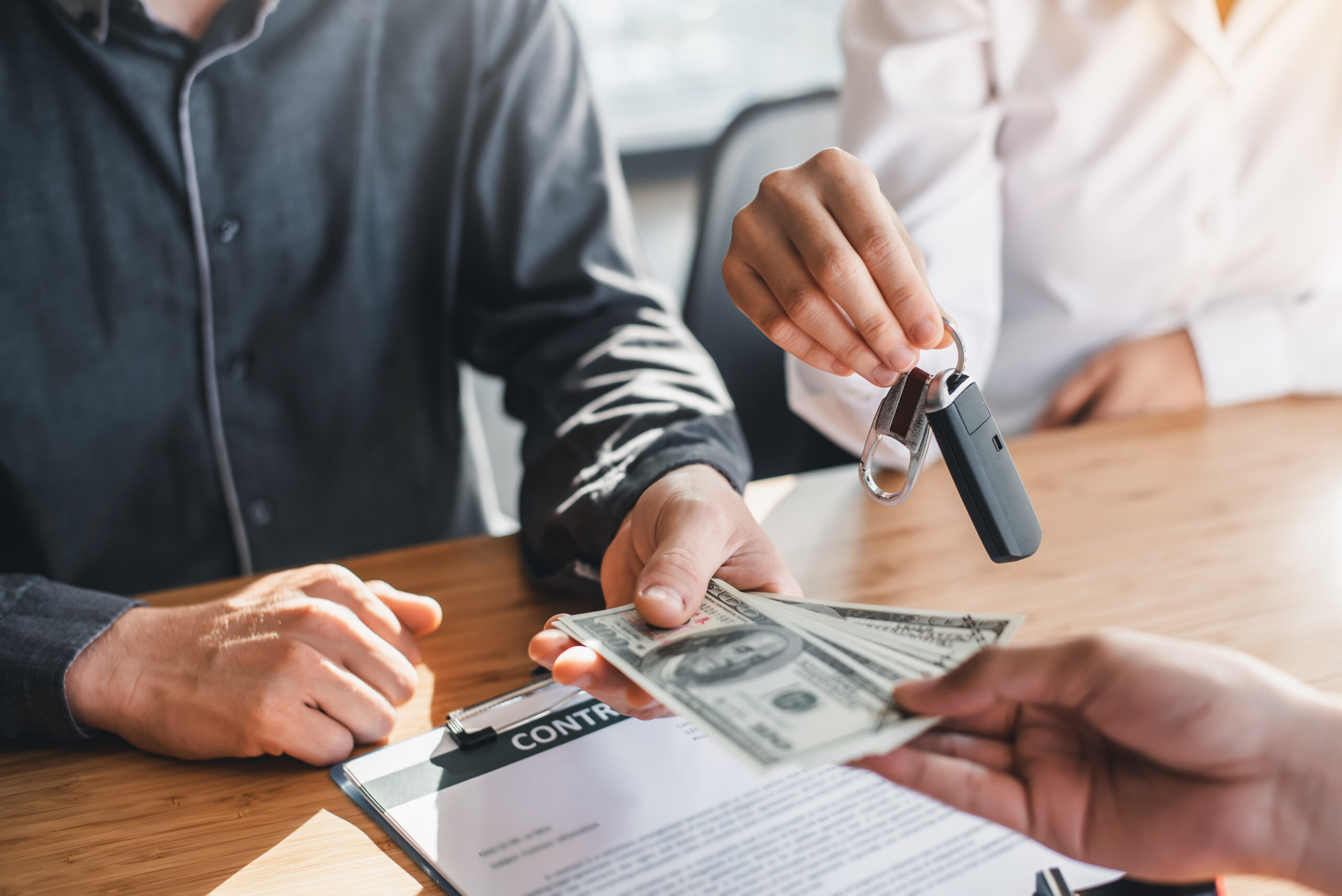 Business signing a contract buy - sell car. Young couple is signing buy or sales car contract and gets the key for the new car.